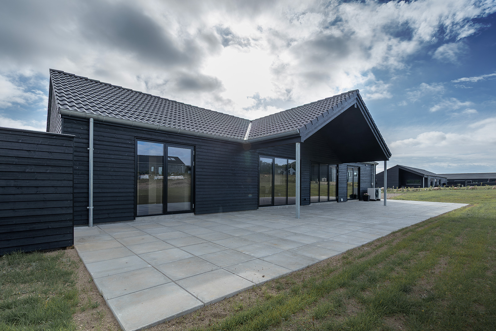 Terrasse ved sommerhus med Vindunor Nor48 træ/alu terrassedøre og vinduer med sort alu udvendigt.