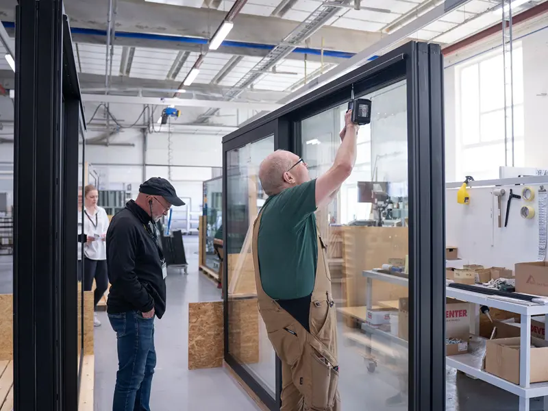 Åben Fabrik 2025 -  gæster på rundvisning kommer forbi skydedørskim der har travlt med at samle en skydedør.