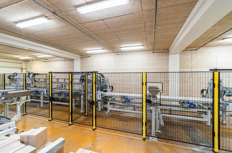 Limdyvel overbliksbillede, hvor man bag et gitter kan se båndet hvor pindene kører.