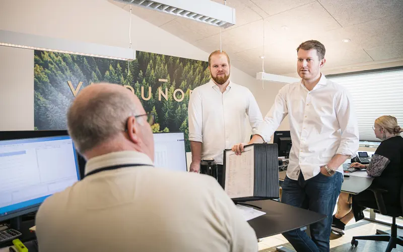 Billede fra vores salgskontor med tre personer. Casper, Mogens og Mikkel. De taler sammen henover et skrivebord.