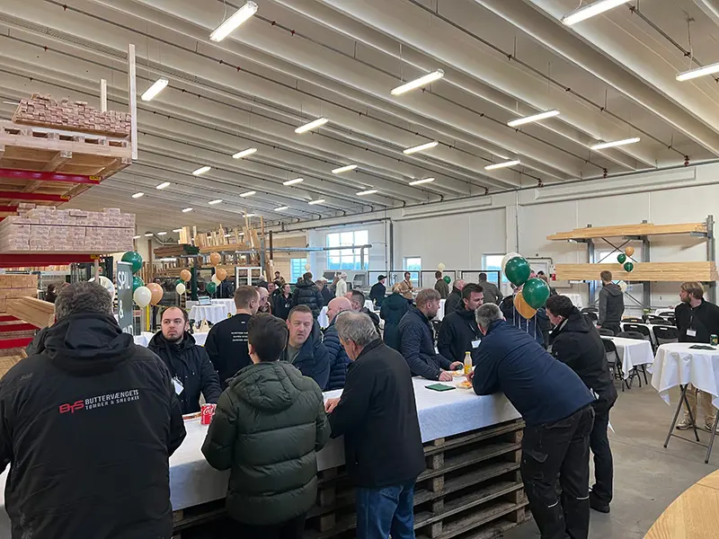 Åben Fabrik 2024 - Gæster spiser hotdogs ved et langt bord lavet af paller.