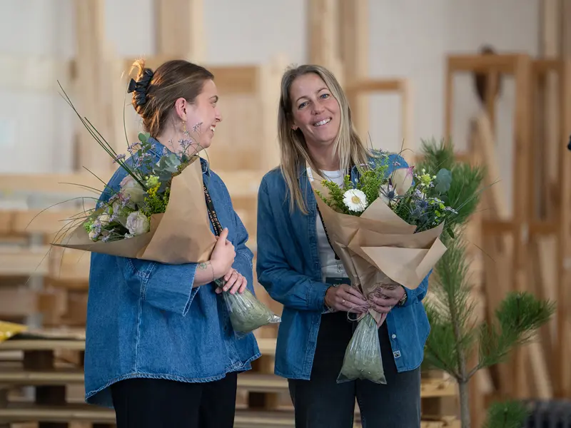 Åben Fabrik 2025 - Mathilde og Karin står med en buket blomster, som tak for  planlægningen af Åben Fabrik 2025.