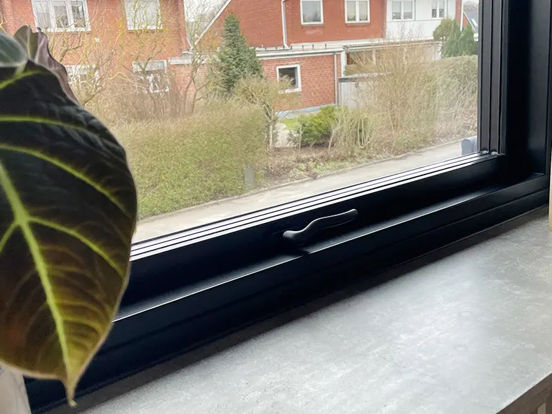 Nærbillede af et topstyret vindue i sort med sort greb