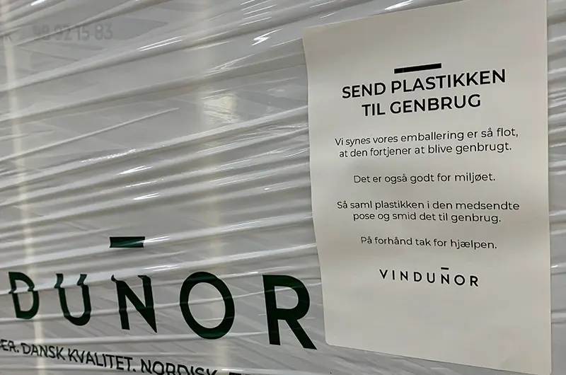 Closeup af det klistermærke vi sætter på færdige elementer. Der står at man skal smide plastikken til genbrug og at vi medsender en pose.