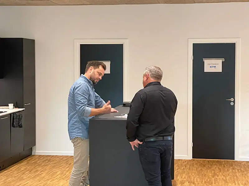 Boligkøb i blinde besøger udstillingen i Rødovre. Jes Vejby snakker med arkitekten ved et højt bord.