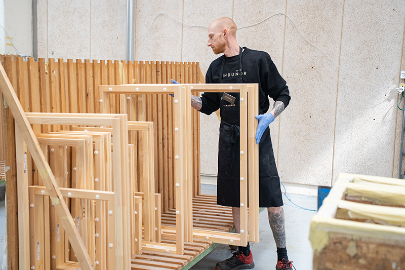 Medarbejder sætter en fyrretræsramme på en vogn efter endt slibning.