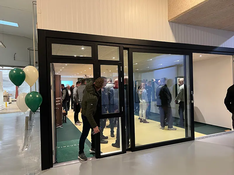 Åben Fabrik 2023 - Mange gæster i showroomet med vinduer og skydedør.