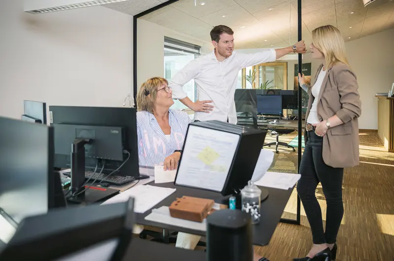 Connie, Caroline og Casper taler sammen på salgskontoret.