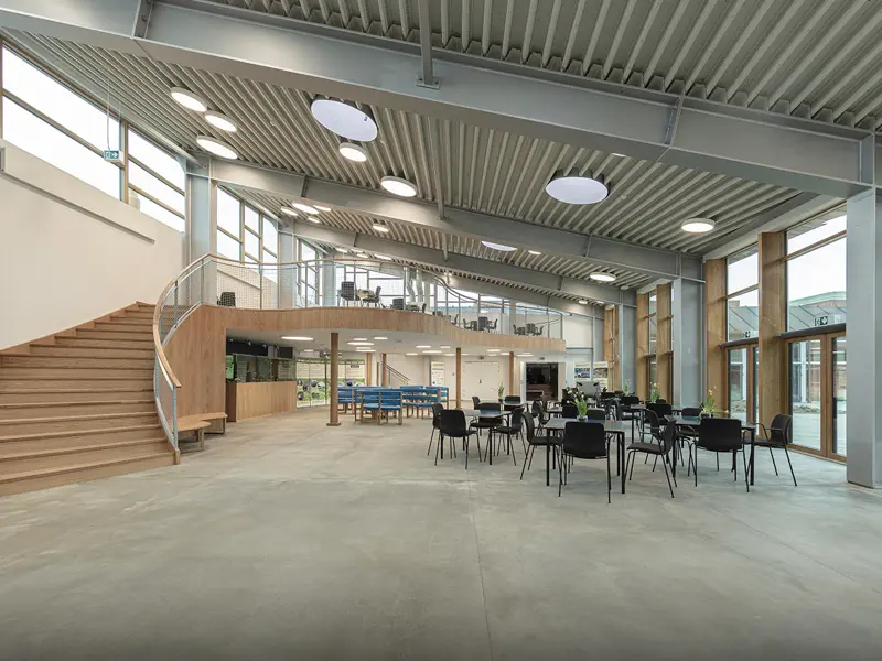 oversigtbillede indvendigt af fælleslokale med masser lysindfald fra det store glasparti der er lavet i lakeret fyrretræ - reference Nordsøen parken