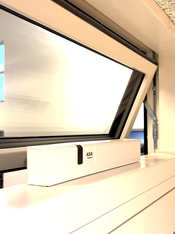 Elektronisk vinduesåbner AXA Remote 2.0 vist på et åbent vindue indefra.