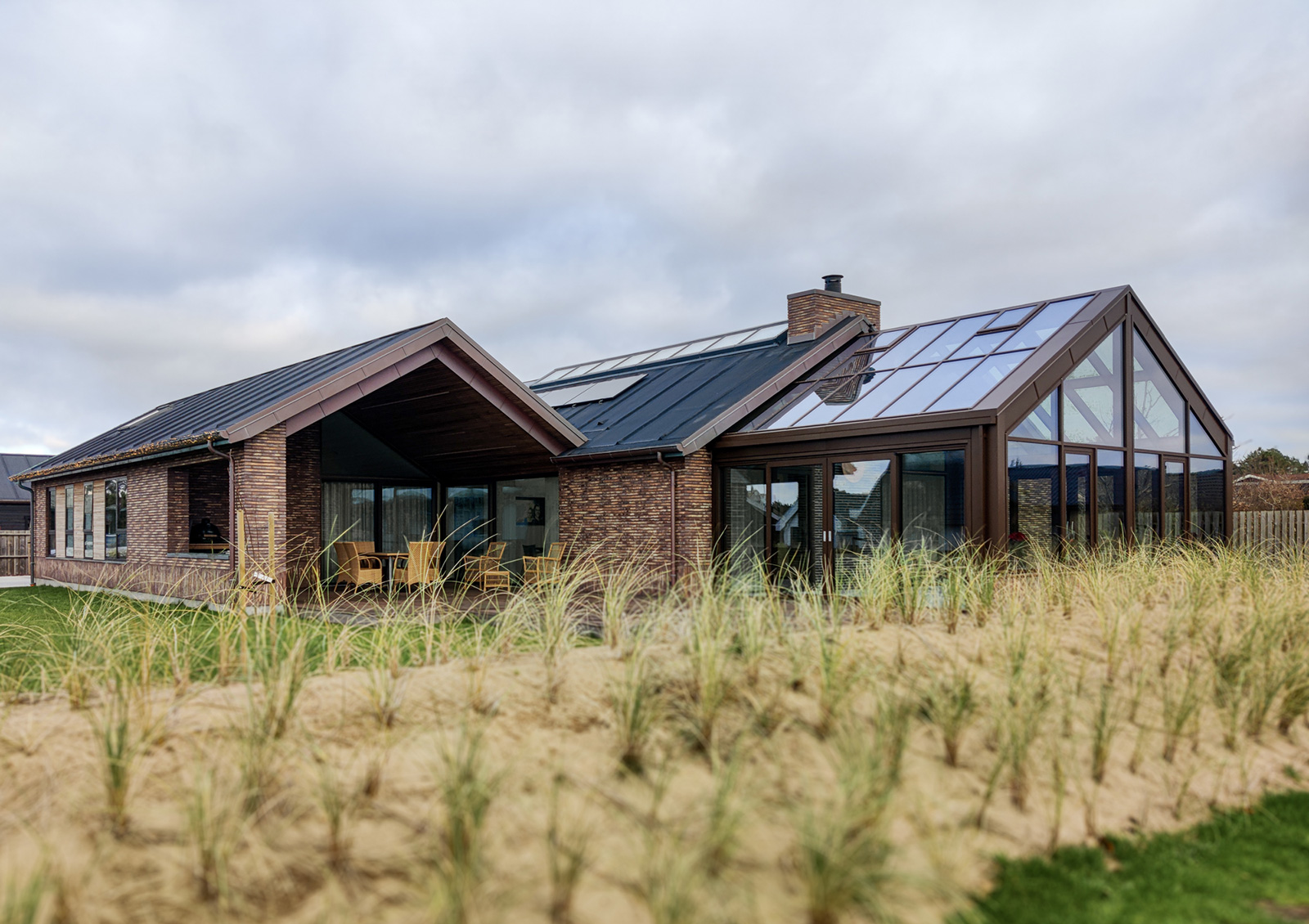 Privatbolig i Blokhus set udefra lidt på afstand, hvor man kan se orangeri og en overdækket terrasse.