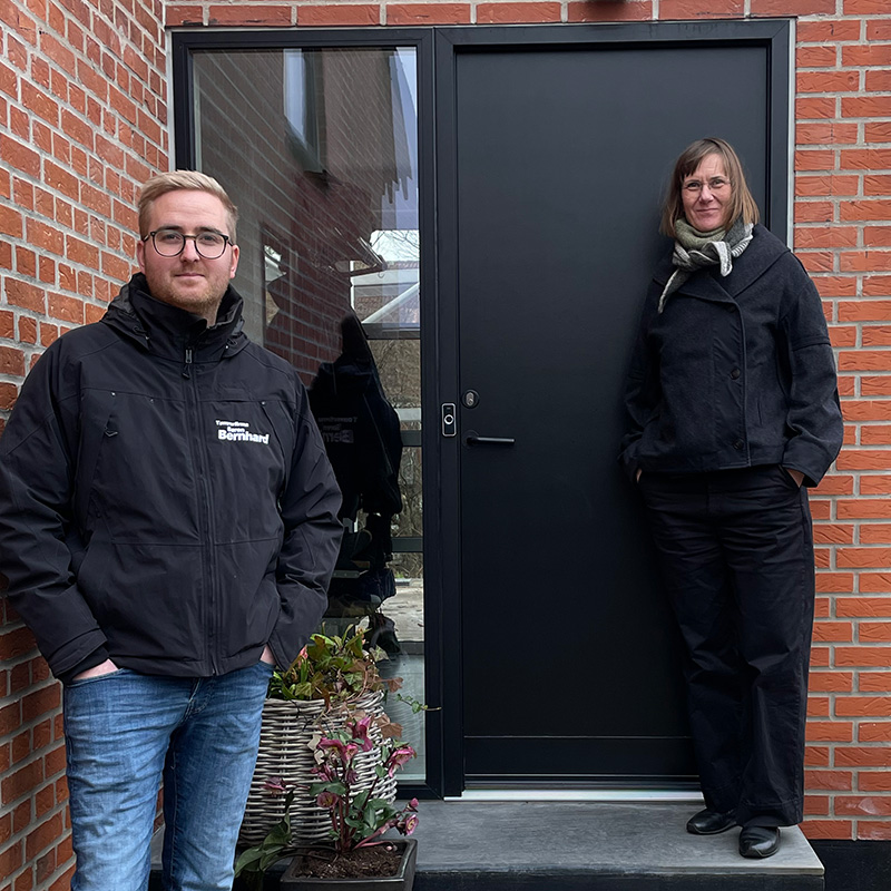 Tømrer og husejere står ude foran facedøren 