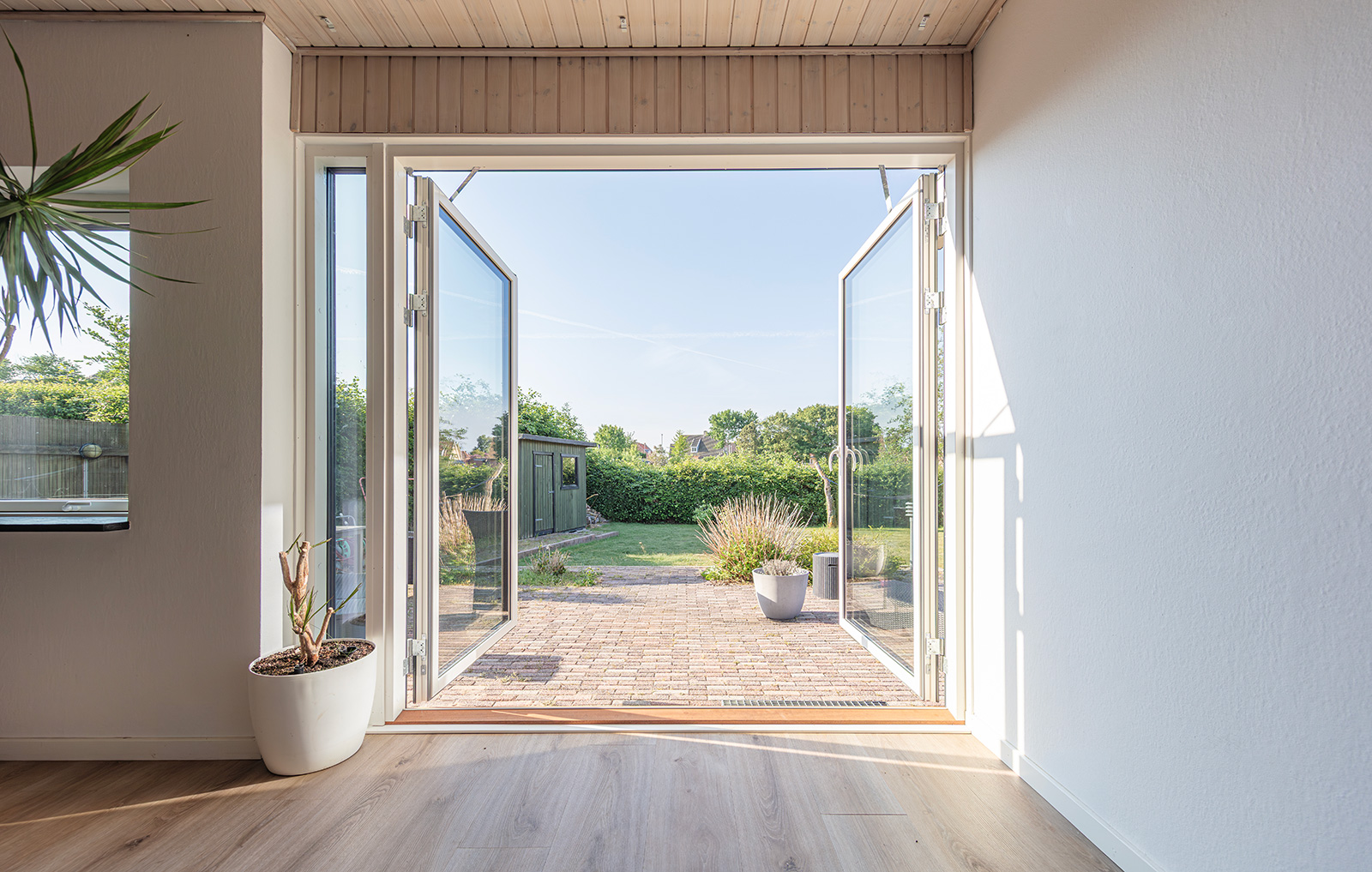 Fuldt åbent træ/alu vinduesdør mod terrasse og have