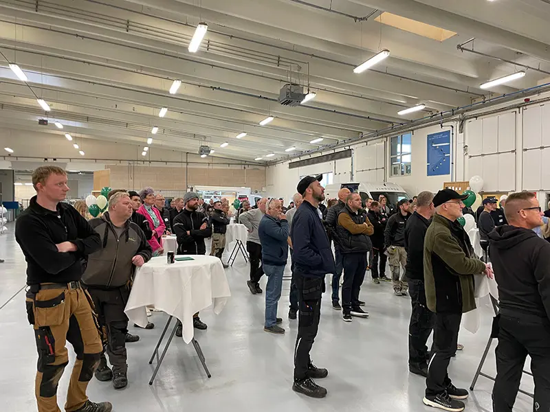 Åben Fabrik 2023 - Gæster står rundt om cafeborde og lytter til Henriks tale.
