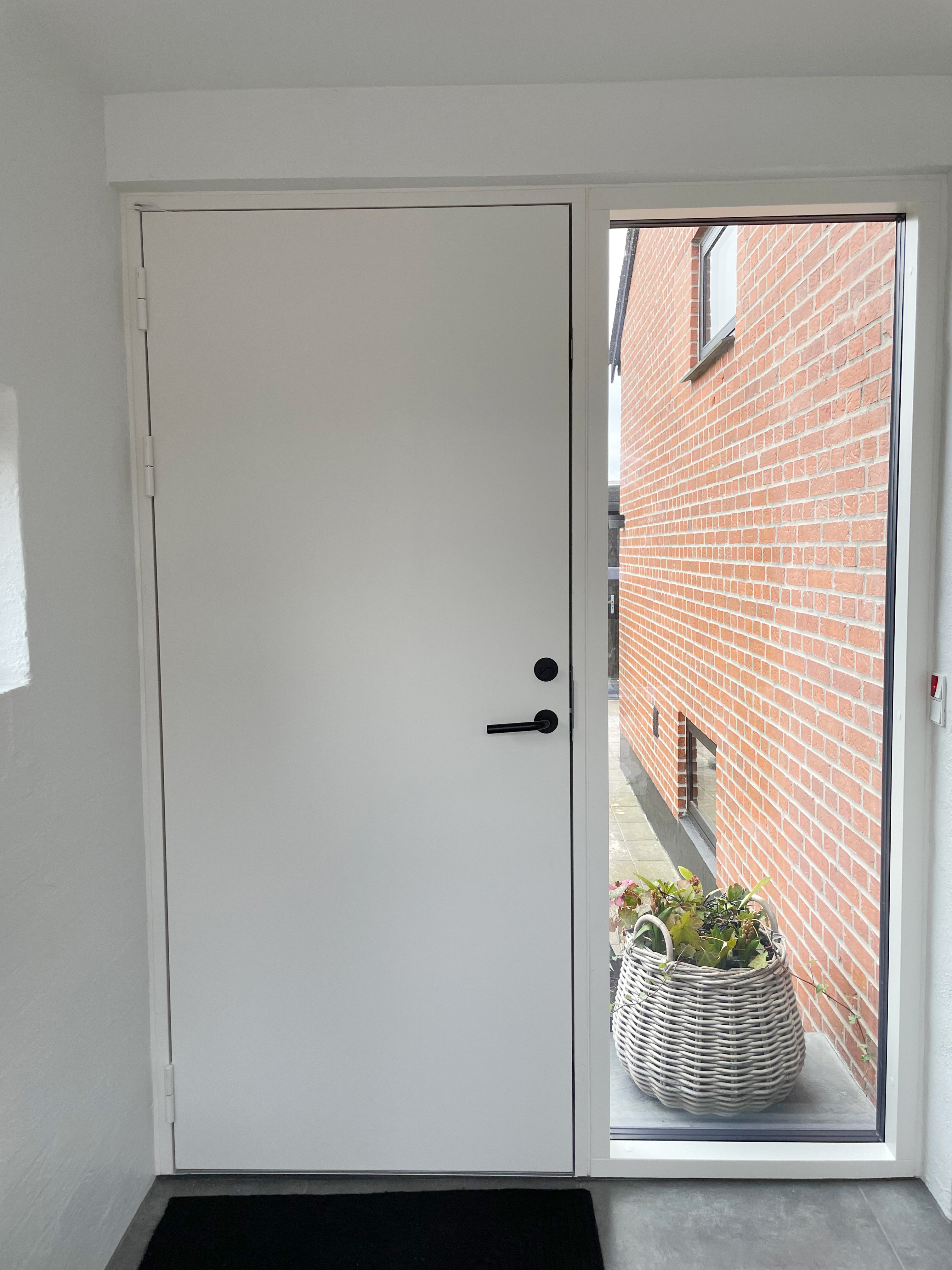 Pladedør i ren hvid med hvide beslag og et sort greb. 