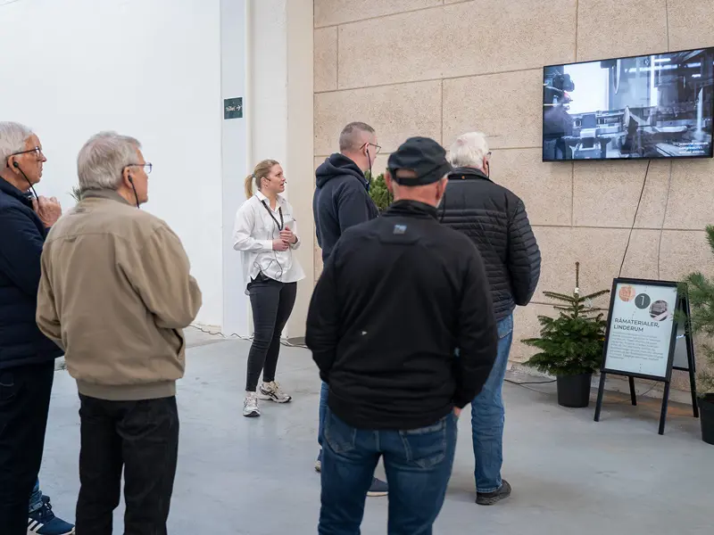 Åben Fabrik 2025 - 5 gæster på rundvisning hvor de ser en video fra Linderum. Caroline fortæller hvad der sker.