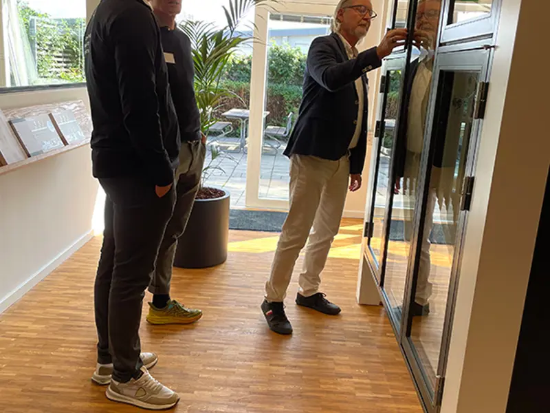 Et vindueselement studeres i detaljerne er 3 gæster til receptionen.