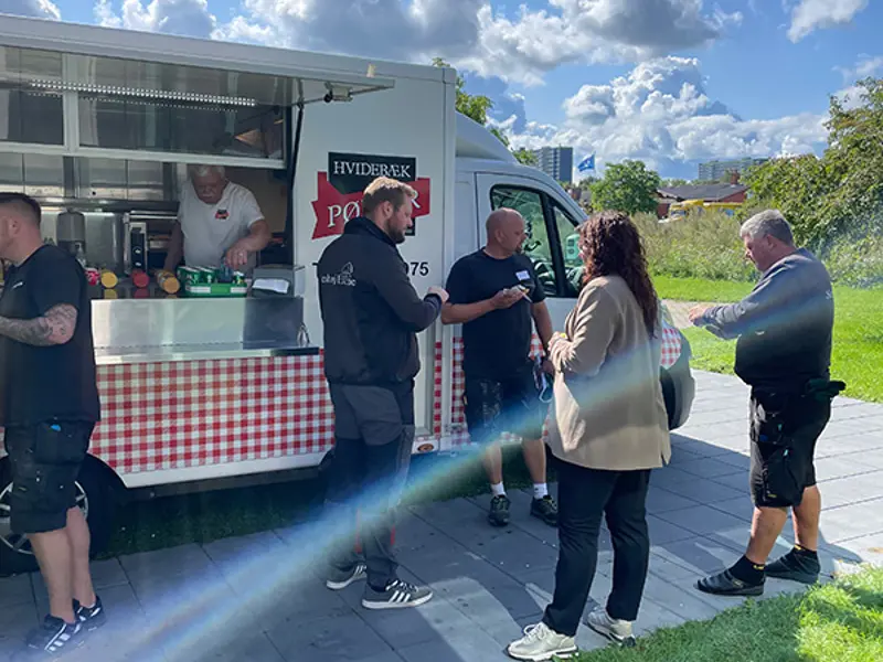 Pølsevognen serverer hotdogs til gæsterne ved receptionen. Der er blå himmel og godt vejr.
