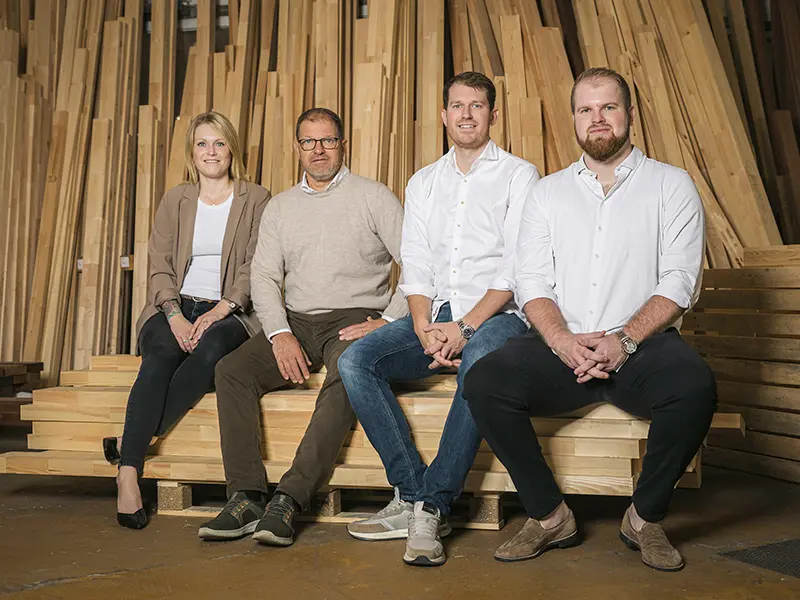 Caroline, Mikkel, Casper og Henrik sidder på palle med stabler af pinde.